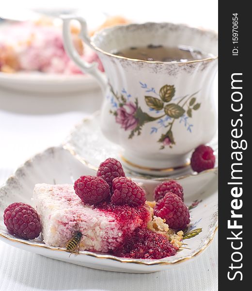 Cheesecake  with raspberry on plate and cup of tea. Cheesecake  with raspberry on plate and cup of tea