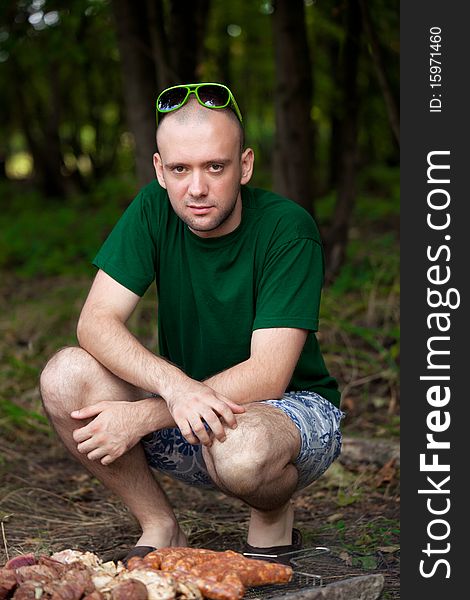 Man sitting near barbecue fire. Man sitting near barbecue fire