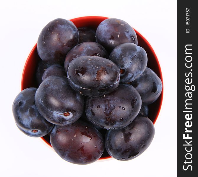 Plums in a bowl on white background