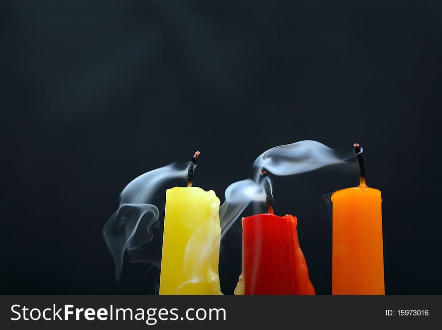 Three colored extinguished candles with smoke on black background. Three colored extinguished candles with smoke on black background