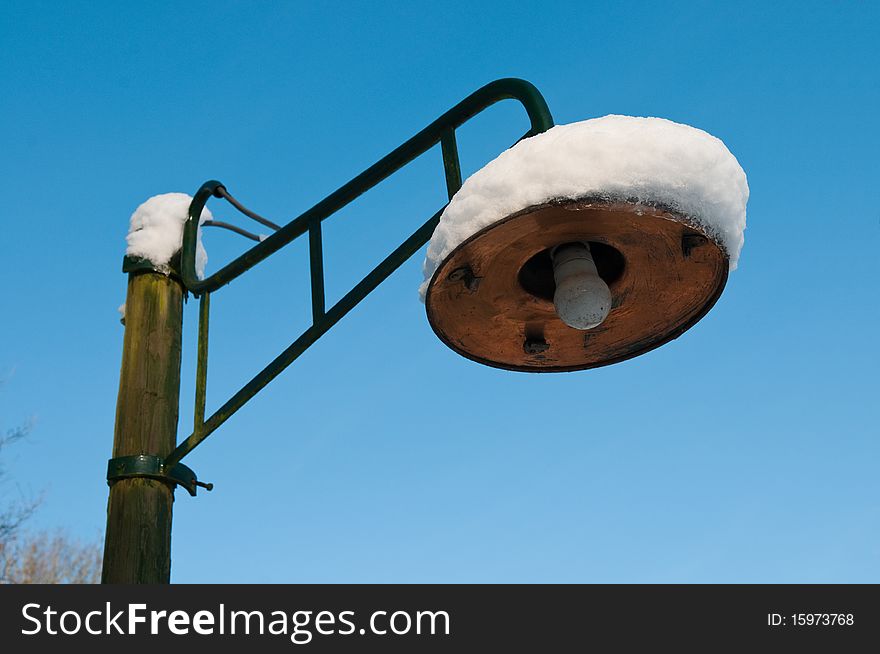 A retro street lantern with snow on it