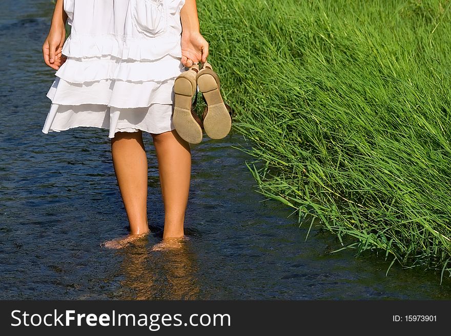 Girl, standing in the cool water, holding her shoes. Girl, standing in the cool water, holding her shoes