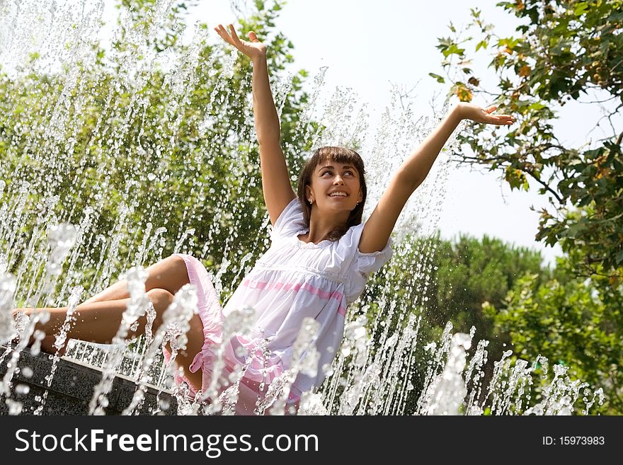 Beautiful woman sitting among the streams of the fountain. Beautiful woman sitting among the streams of the fountain