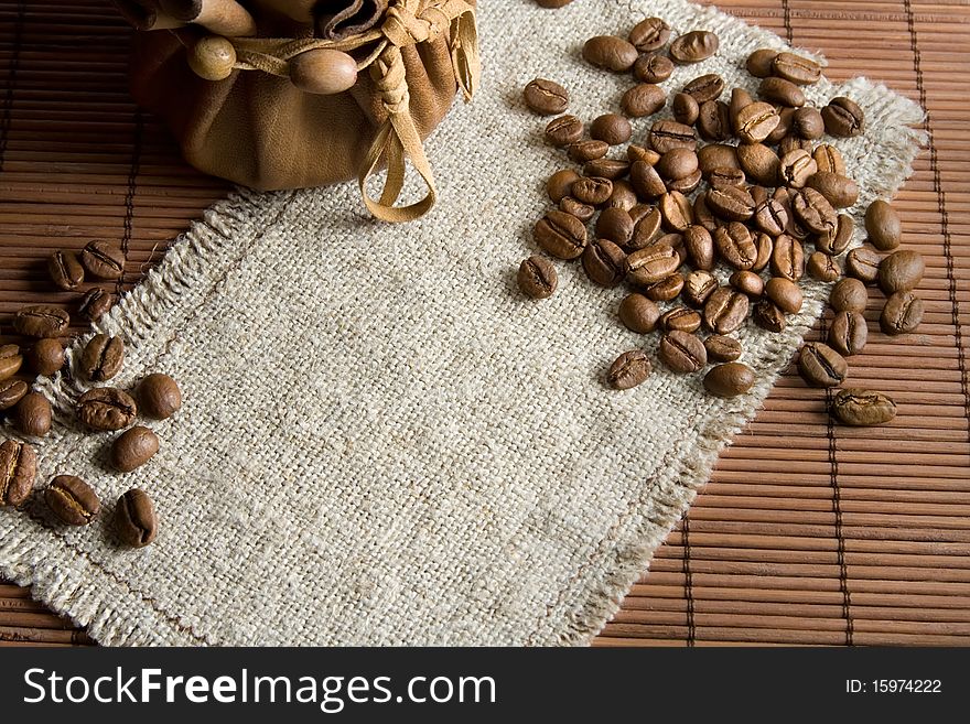 Background with roasted coffee beans and small leather pack. Background with roasted coffee beans and small leather pack