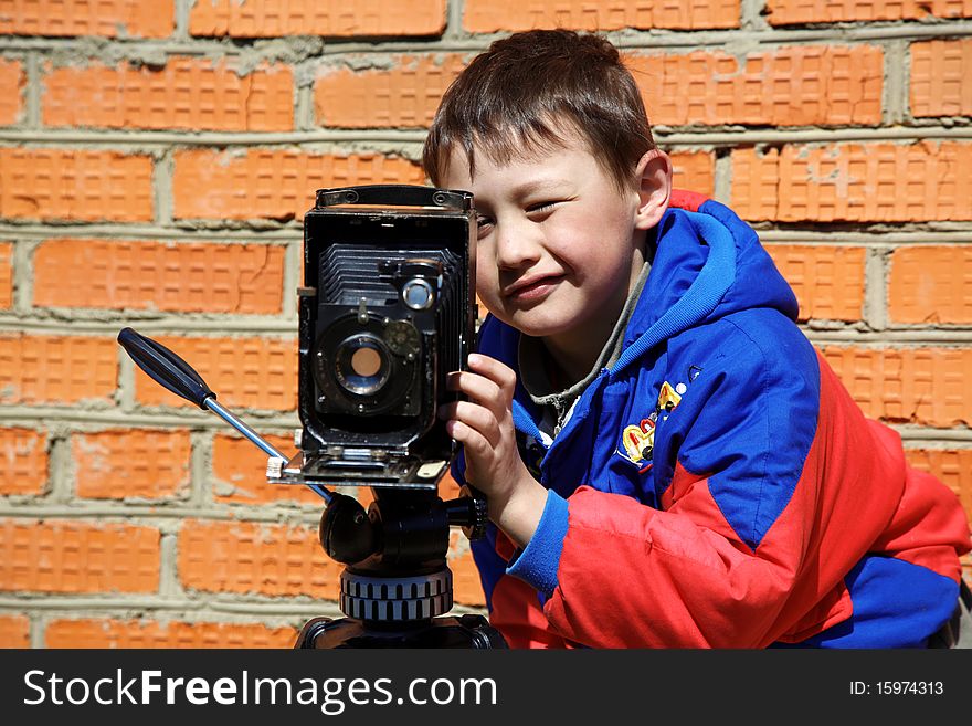 Kid making a shot with retro camera on tripod