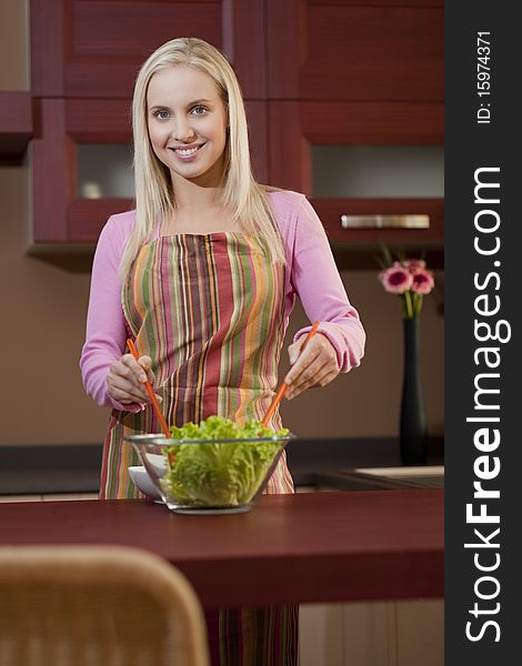 Happy young woman having fun in a kitchen preparing a vegetable salad. Happy young woman having fun in a kitchen preparing a vegetable salad.