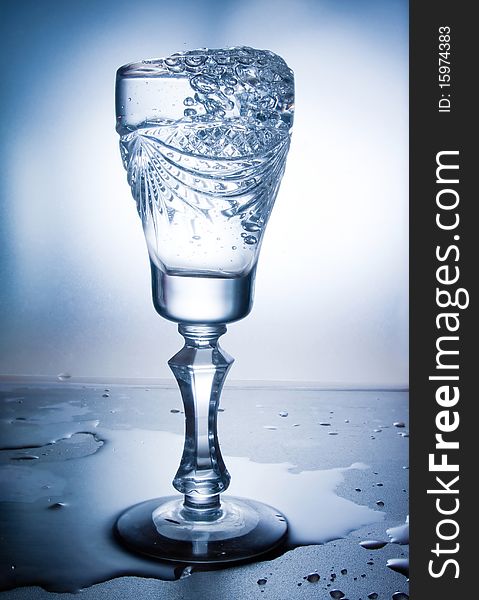 Water splash in glass on blue background