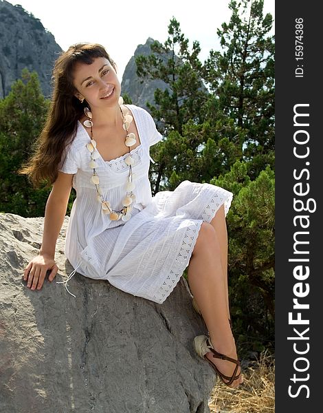 Young girl in white dress sitting on the rock. Young girl in white dress sitting on the rock