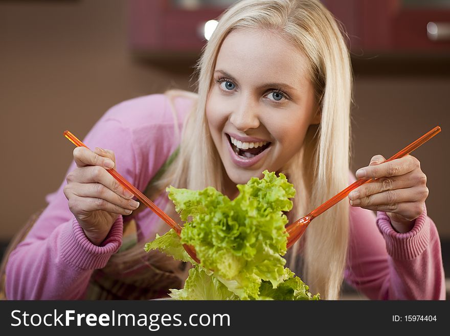 Happy young woman having fun in a kitchen preparing a vegetable salad. Happy young woman having fun in a kitchen preparing a vegetable salad.