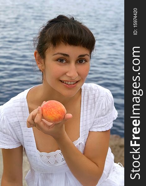 Young girl with the peach near the sea