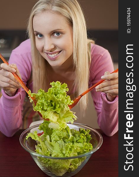 Happy young woman having fun in a kitchen preparing a vegetable salad. Happy young woman having fun in a kitchen preparing a vegetable salad.