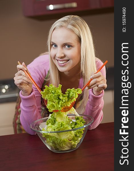 Happy young woman having fun in a kitchen preparing a vegetable salad. Happy young woman having fun in a kitchen preparing a vegetable salad.