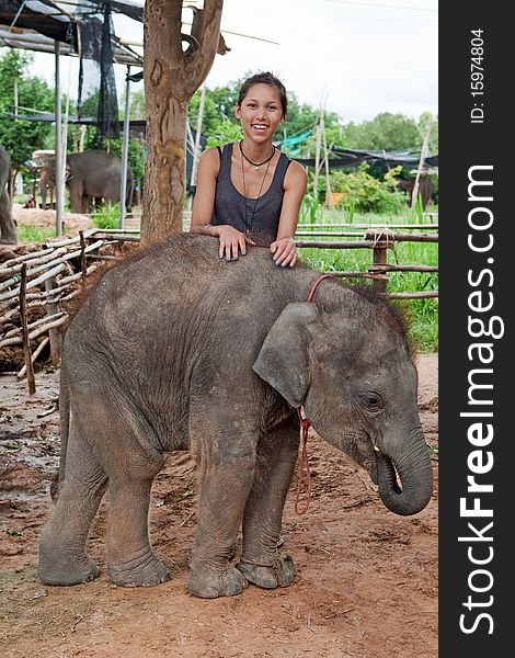 Teenager with baby elephant, delightful young animal of three month