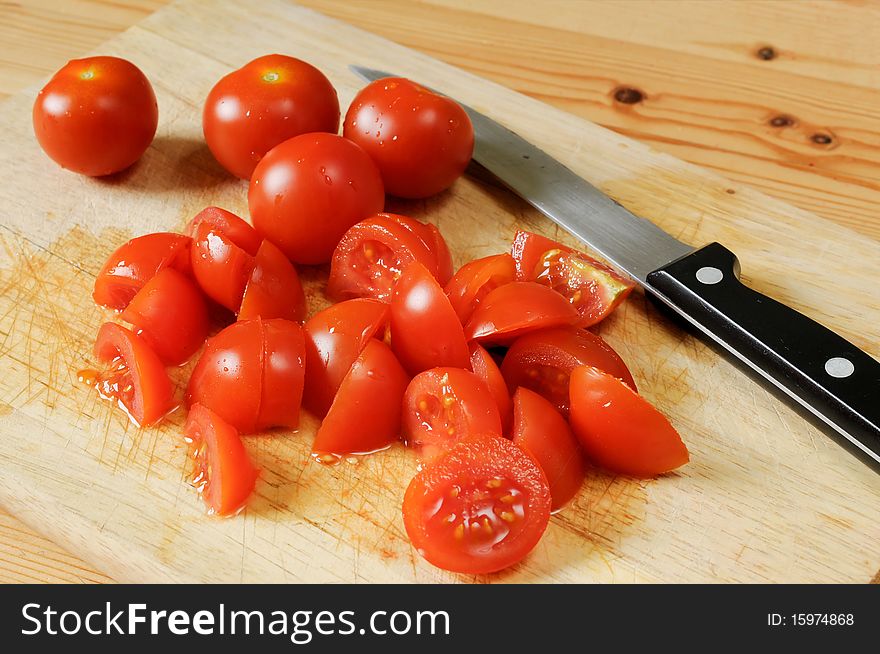 A few of tomatoes on a wooden plate side by side. some tomatoes cutted
