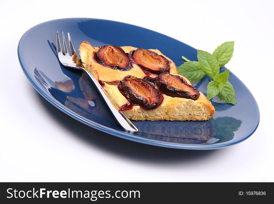 Piece of Plum Pie on a blue plate decorated with a mint twig