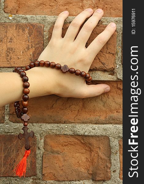 Hand with a prayer rope on the brick wall background. Hand with a prayer rope on the brick wall background