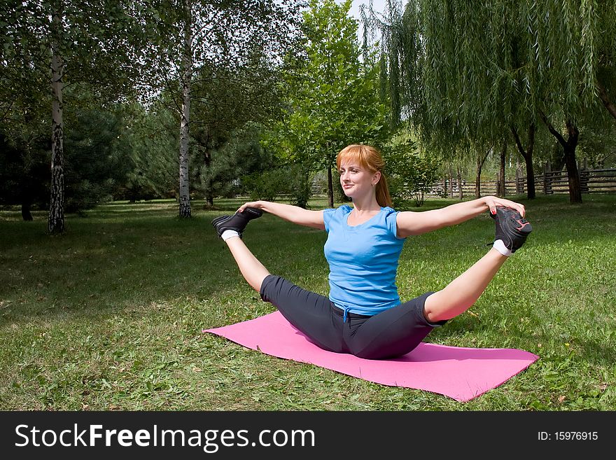 Woman engages in yoga, sits on buttocks in splits. Woman engages in yoga, sits on buttocks in splits