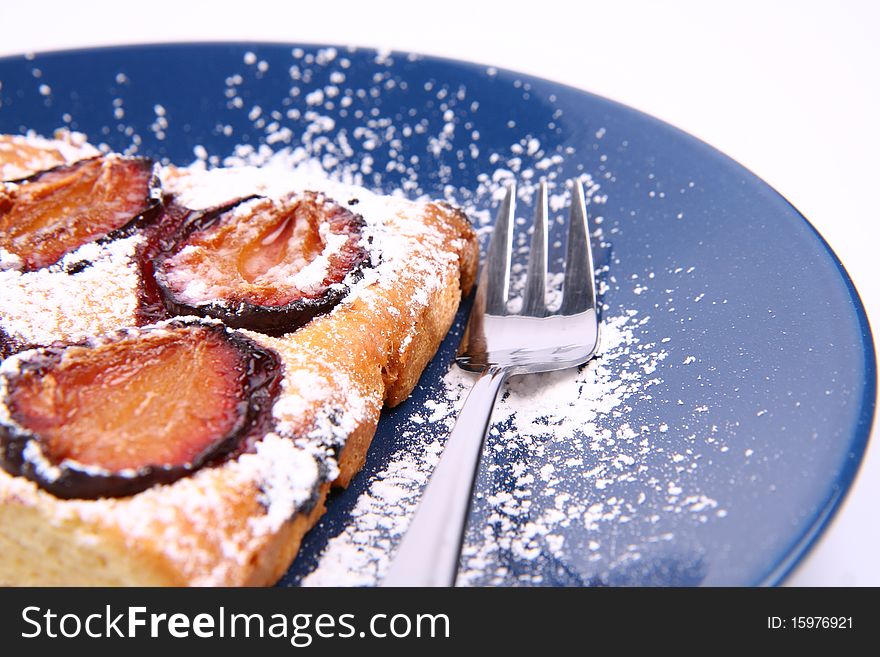 Piece of Plum Pie covered with powder sugar on a blue plate