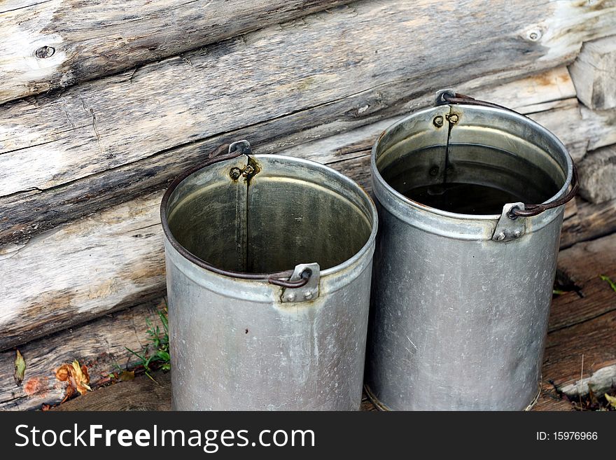 Filling steel bucket with water from well. Filling steel bucket with water from well