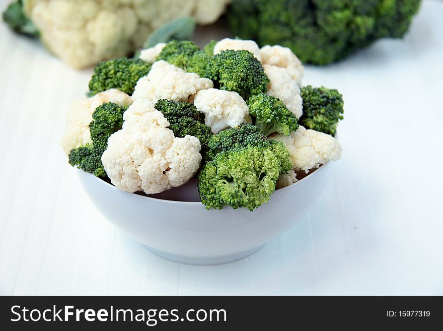 Cauliflower and broccoli in a white cup on the beige background