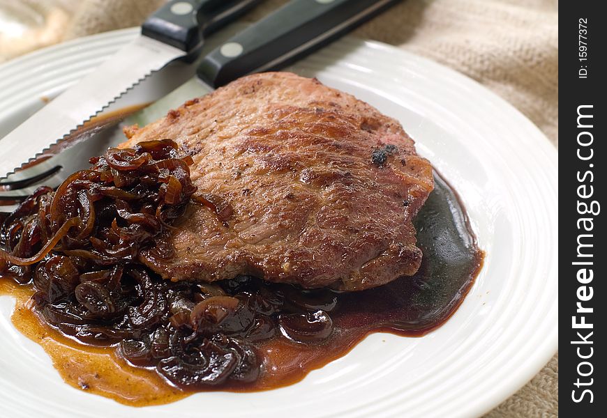 A  steak  with fried onions on top on plate. A  steak  with fried onions on top on plate