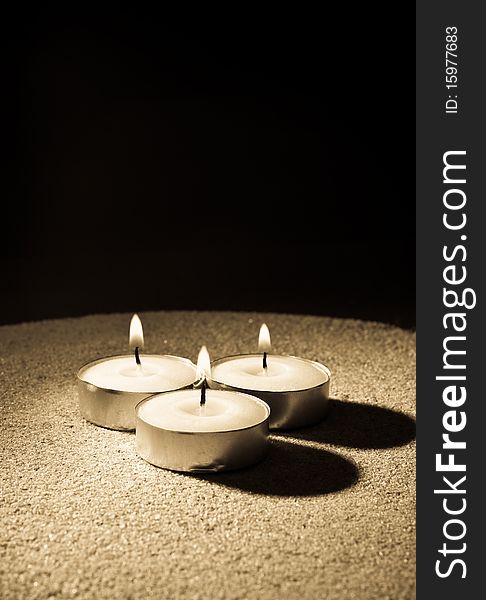 Three Lit Candles on Sand in Single Point Abstract Lighting. Three Lit Candles on Sand in Single Point Abstract Lighting