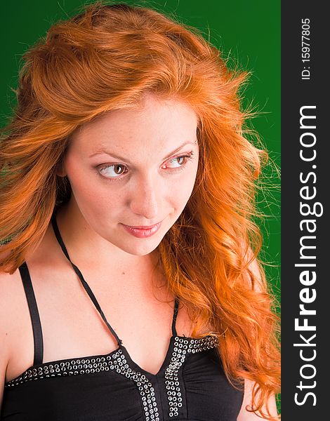 Beautiful red-haired woman with a look of interrogative in black sarafan on a green background closeup. Beautiful red-haired woman with a look of interrogative in black sarafan on a green background closeup