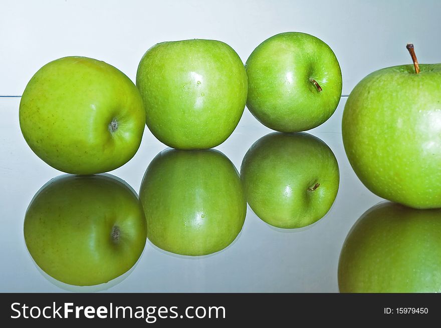 Green apples on reflexive glass base