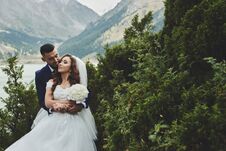Beautiful Wedding Photo On Mountain Lake. Happy Asian Couple In Love, Bride In White Dress And Groom In Suit Are Photographed Agai Royalty Free Stock Photos