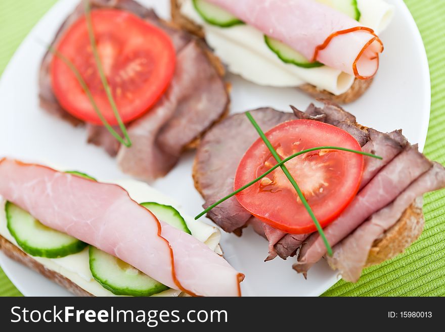 Delicious appetizer of cheese, ham, beef and cucumber on rye bread. Shallow DOF