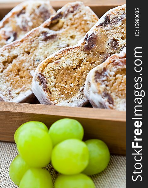 Slices of stollen cake in a wooden box with fresh green grapes. Shallow DOF. Slices of stollen cake in a wooden box with fresh green grapes. Shallow DOF