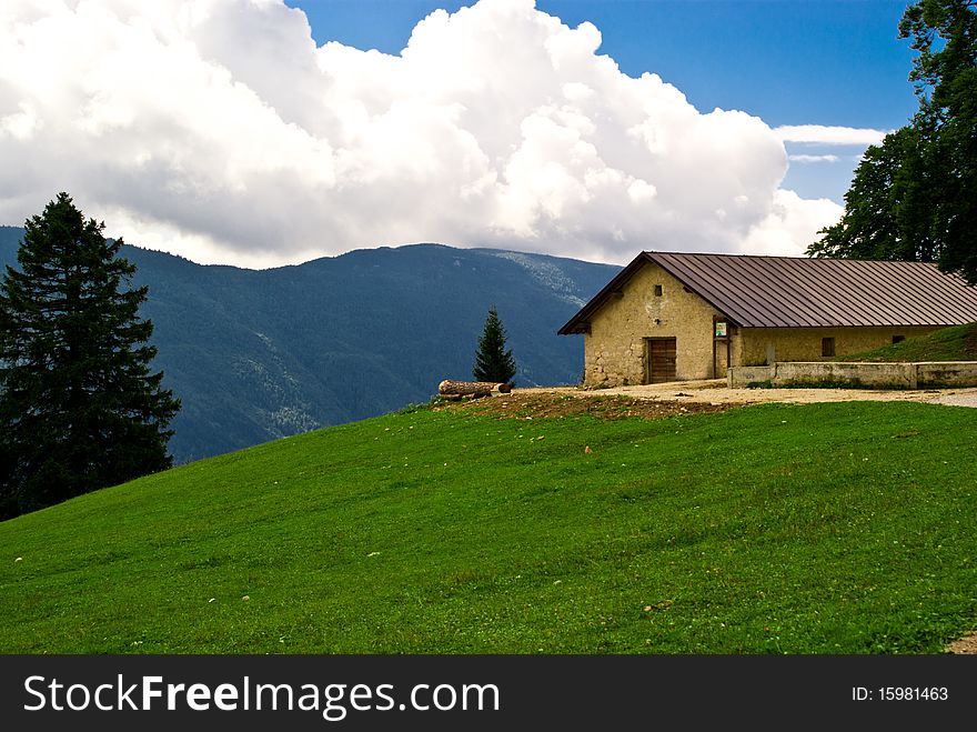 Chalet atop a mountain in Trentino, a summer day with a green