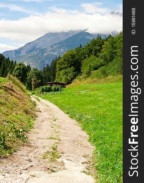 Country road near a meadow with a backdrop of mountains and blue in summer Journal