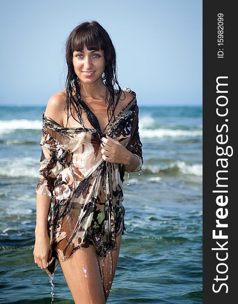 Young woman in a wet beach dress with bare shoulders standing in ocean water. Tenerife, Spain. Young woman in a wet beach dress with bare shoulders standing in ocean water. Tenerife, Spain.