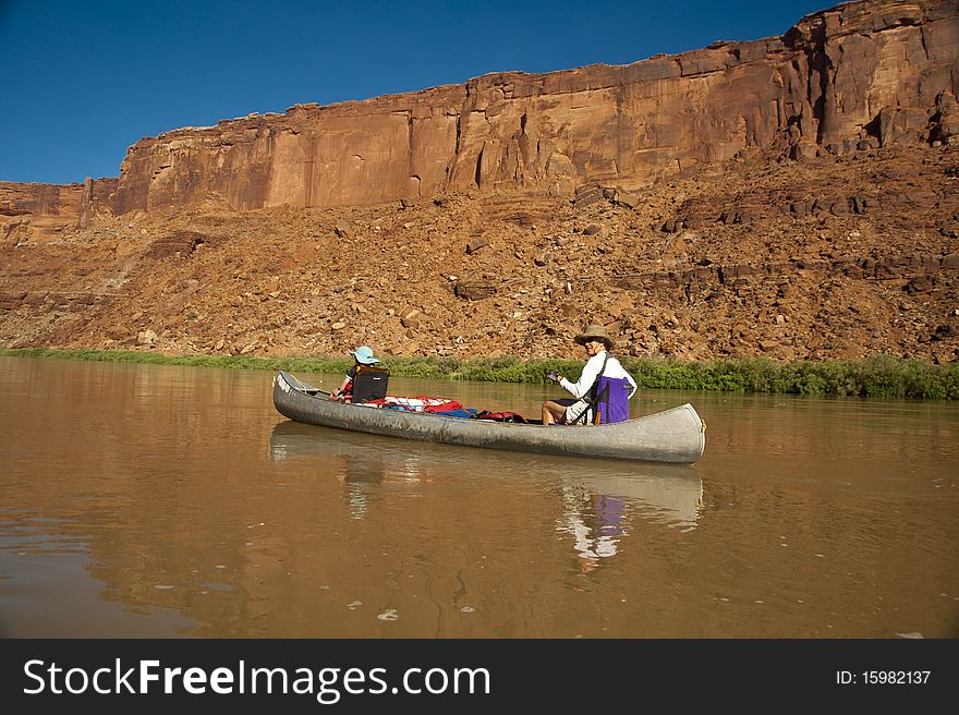 Mother and daughter canoeing on a calm blue river in the desert country of Utah. Mother and daughter canoeing on a calm blue river in the desert country of Utah