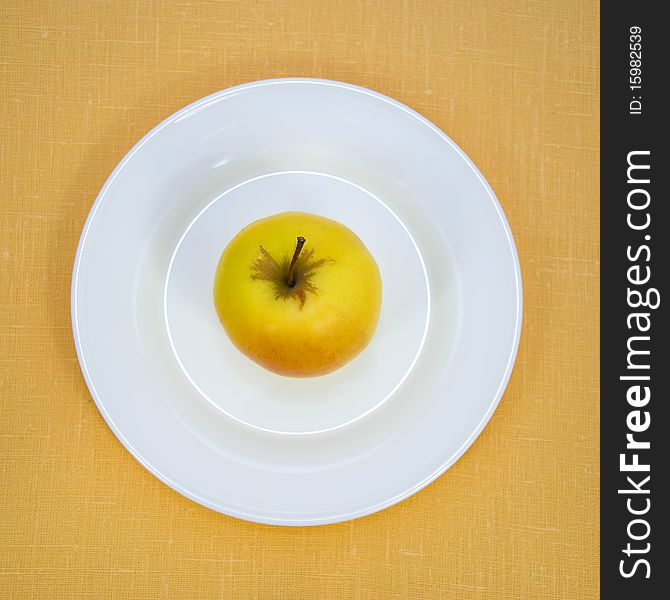 Apple on white plate over linen background.