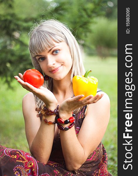 Girl smiling, holding a yellow pepper and red tomato. Girl smiling, holding a yellow pepper and red tomato