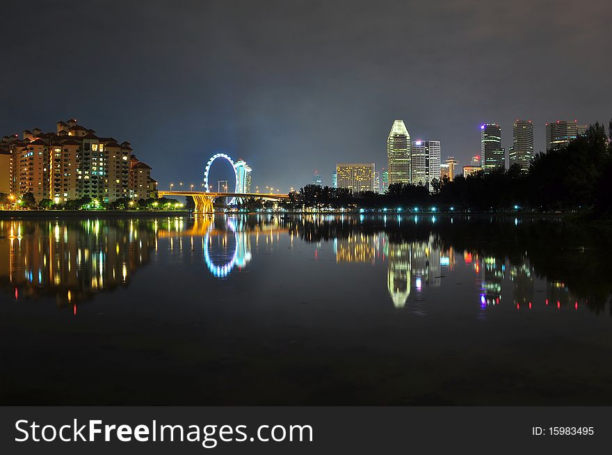 A river surrounded by residential, bridge, Ferris wheel, and some tall buildings. A river surrounded by residential, bridge, Ferris wheel, and some tall buildings