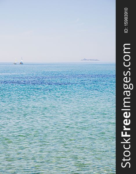 Couple of sailboats sailing into the sea to an island of Sardinia, Italy.