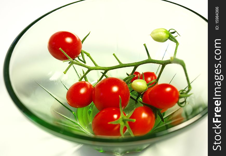 Cluster of cherry tomatoes in a small transparent plate on the white isolated background. Cluster of cherry tomatoes in a small transparent plate on the white isolated background