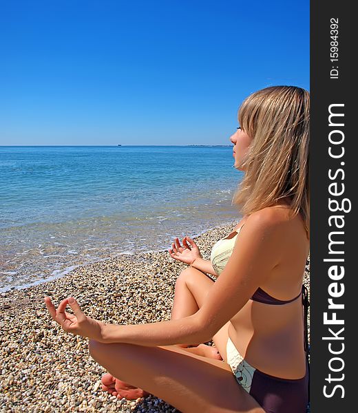 Beautiful girl relaxing on the beach in yoga position