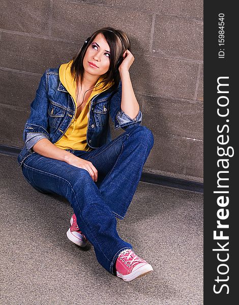 Lovely girl in jean clothing listening a music near brick wall. Lovely girl in jean clothing listening a music near brick wall