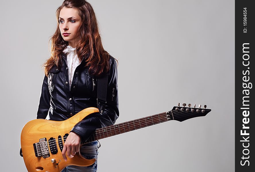 Portrait of a beautiful stylish woman with electric guitar on gray background