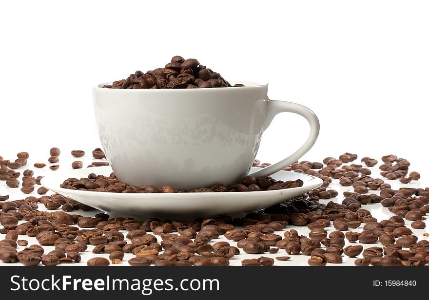 White espresso cup full of beans sat on coffee beans
