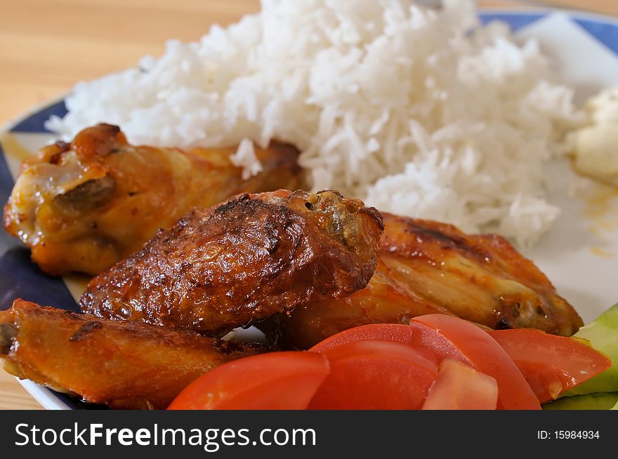 Fried chicken legs with rice and salad on a plate