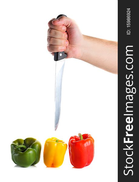 Concept of a hungry man's hand pointing a sharp knife at three colorful peppers isolated on white with copy space