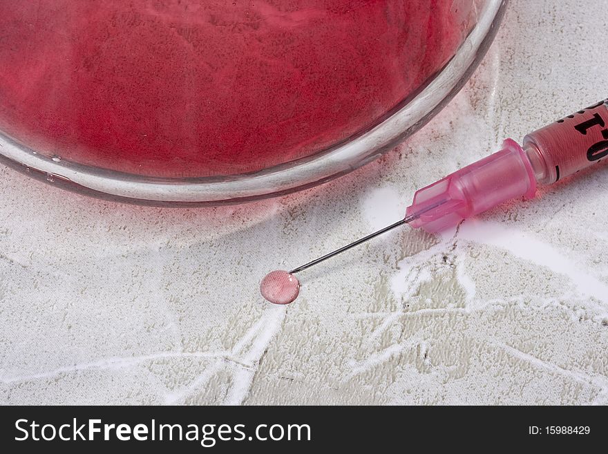 Syringe with pink liquid next to a spill.