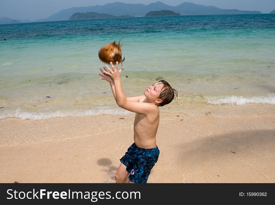 Boy is playing with a coconut on a beach