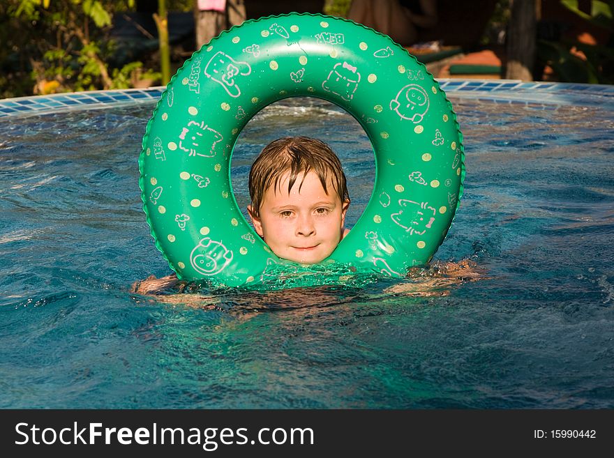 Child enjoys swimming with rubber ring in the pool