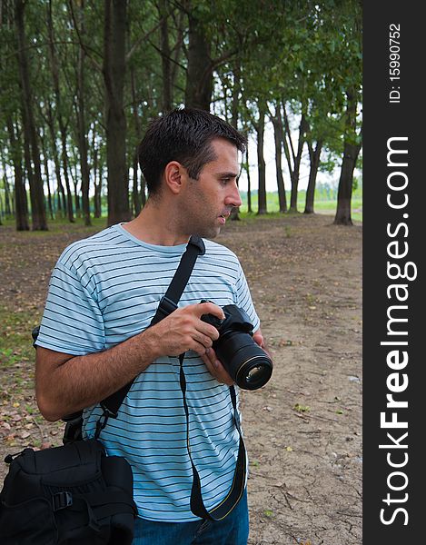 Young photographer looking side-ways, waiting for the photo opportunity outdoors, near a river in woods. Young photographer looking side-ways, waiting for the photo opportunity outdoors, near a river in woods